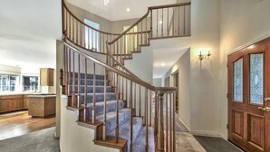 A spacious home interior with a curved staircase, wooden flooring, and a kitchen area. - Huge 7BR/4.5BA - Hot Tub, Ping Pong/Pool Table, Arcade, Gas BBQ (South Lake Tahoe)