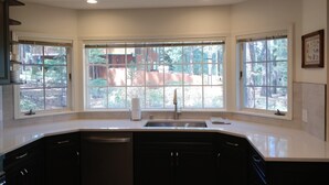 A kitchen with a large window, a sink, and dark cabinets. - Huge 7BR/4.5BA - Hot Tub, Ping Pong/Pool Table, Arcade, Gas BBQ (South Lake Tahoe)