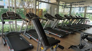 A gym with multiple treadmills and exercise equipment, large windows, and a view of greenery outside. - The Kith Plus Sukhumvit 113 (Samut Prakan)