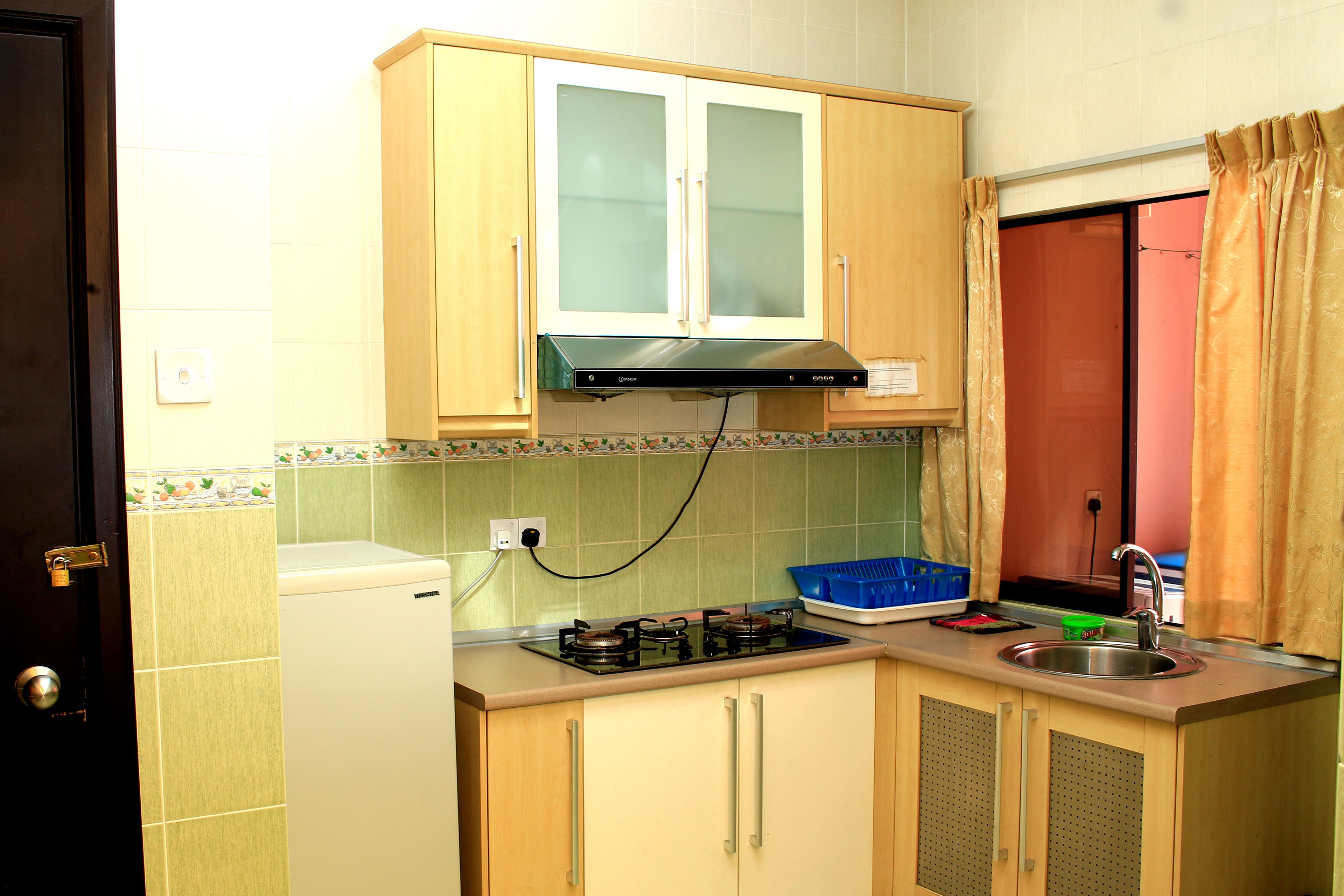 Cocina compacta con estufa a gas, un lavamanos y armarios de madera.