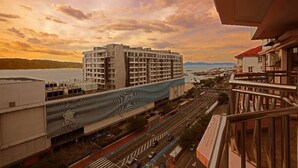 A modern hotel with a unique wave-patterned facade, a view of a busy street, and a body of water in the background. - 1st Choice Vacation Apartments at Marina Court Resort Resort (Kota Kinabalu)