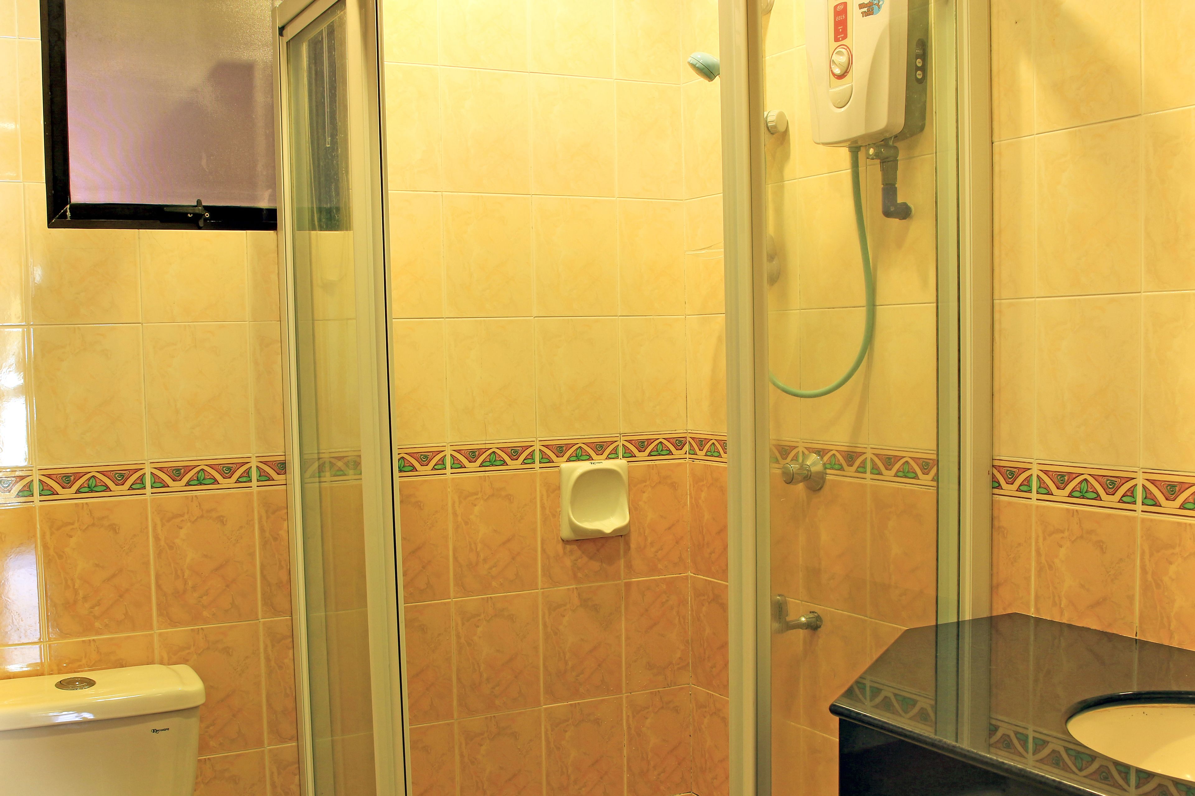 A bathroom with a glass-enclosed shower, a toilet, and a sink with a mirror.