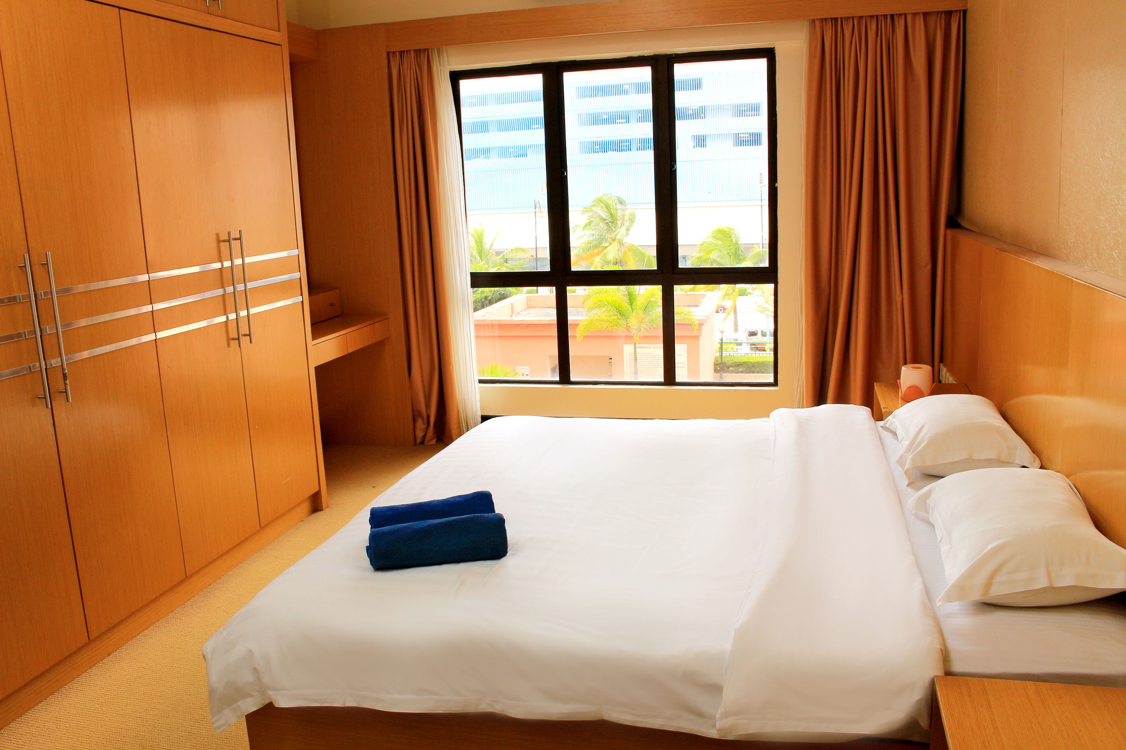 Quarto de hotel com uma cama grande, um guarda-roupa e uma janela com cortinas.