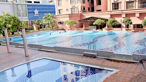 A swimming pool with tiled edges and steps leading into the water, surrounded by a building with balconies and a sign for a sushi restaurant. - 1st Choice Vacation Apartments at Marina Court Resort Resort (Kota Kinabalu)