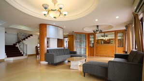 A spacious living area with a curved staircase, a large gray sofa, a coffee table, and a chandelier. - 1st Choice Vacation Apartments at Marina Court Resort Resort (Kota Kinabalu)