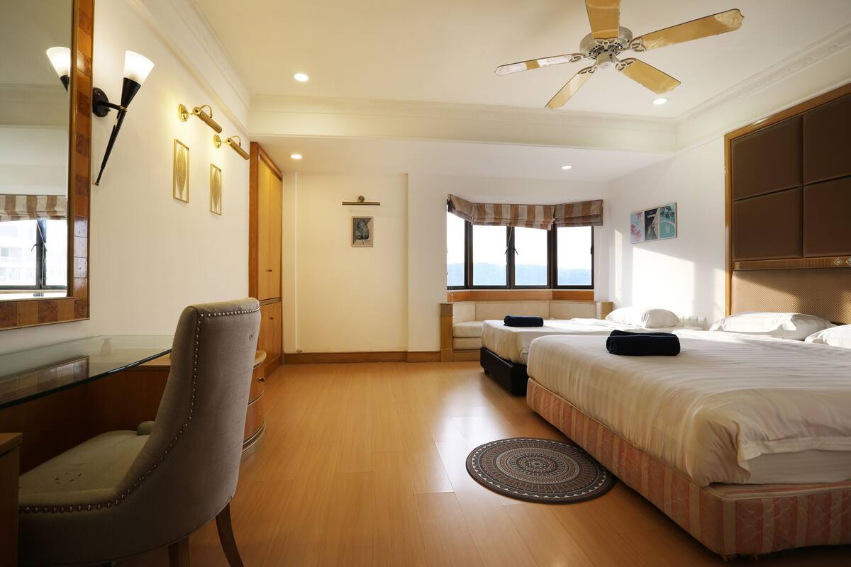 A hotel room with a bed, a desk, a chair, a ceiling fan, and a window with a view.