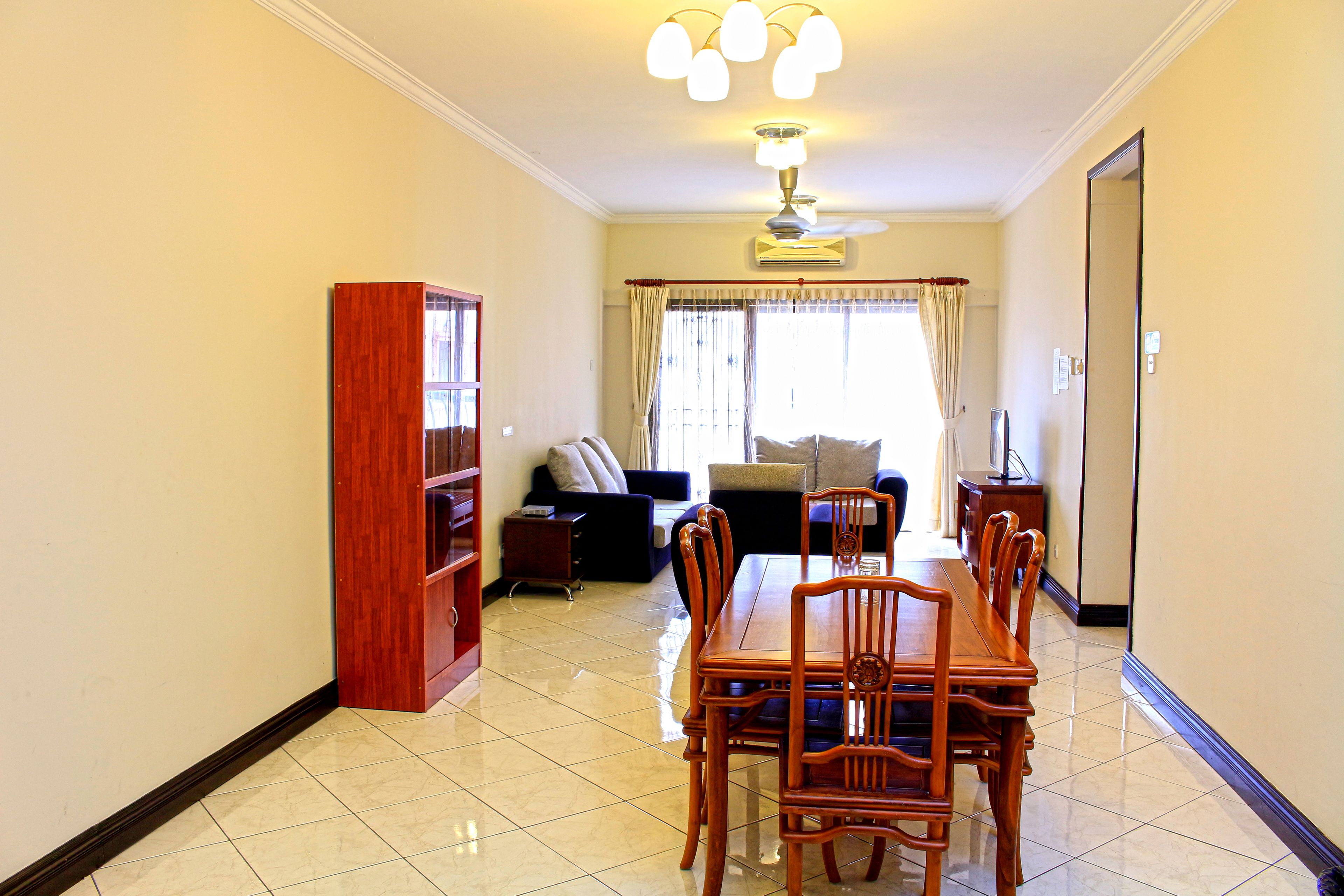A spacious living area with a dining table and chairs, a sofa, and a bookshelf.