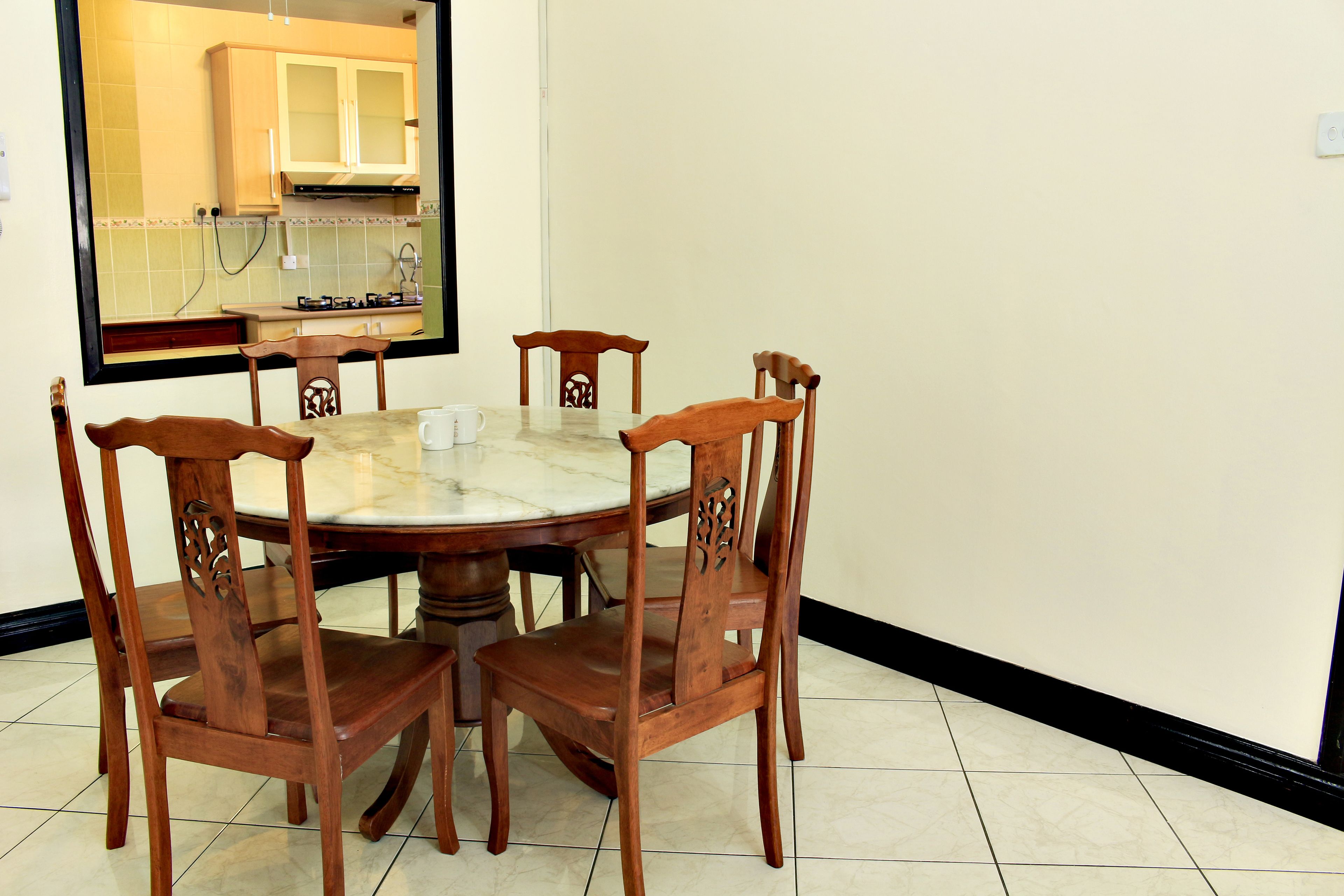 A dining area with a round table and four wooden chairs.