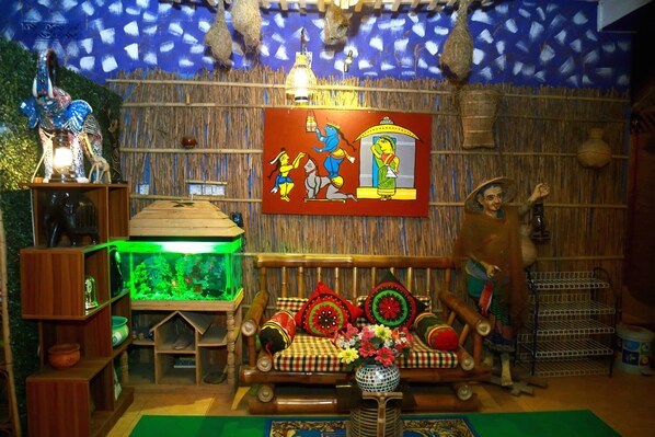 A room with a wooden sofa, a fish tank, and a decorative painting. - Green Leaf Guest House (Sreemangal)