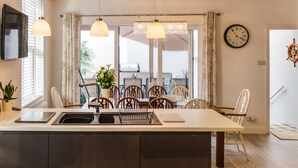Una cocina moderna con una isla central, luces colgantes y un comedor con sillas y una mesa.