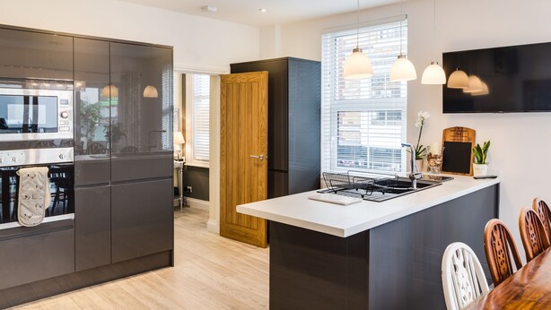 Una cocina moderna con una isla central, electrodomésticos integrados e iluminación colgante.