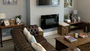 Una sala de estar moderna con un televisor de pantalla plana grande, un sofá de cuero marrón y una mesa de centro.