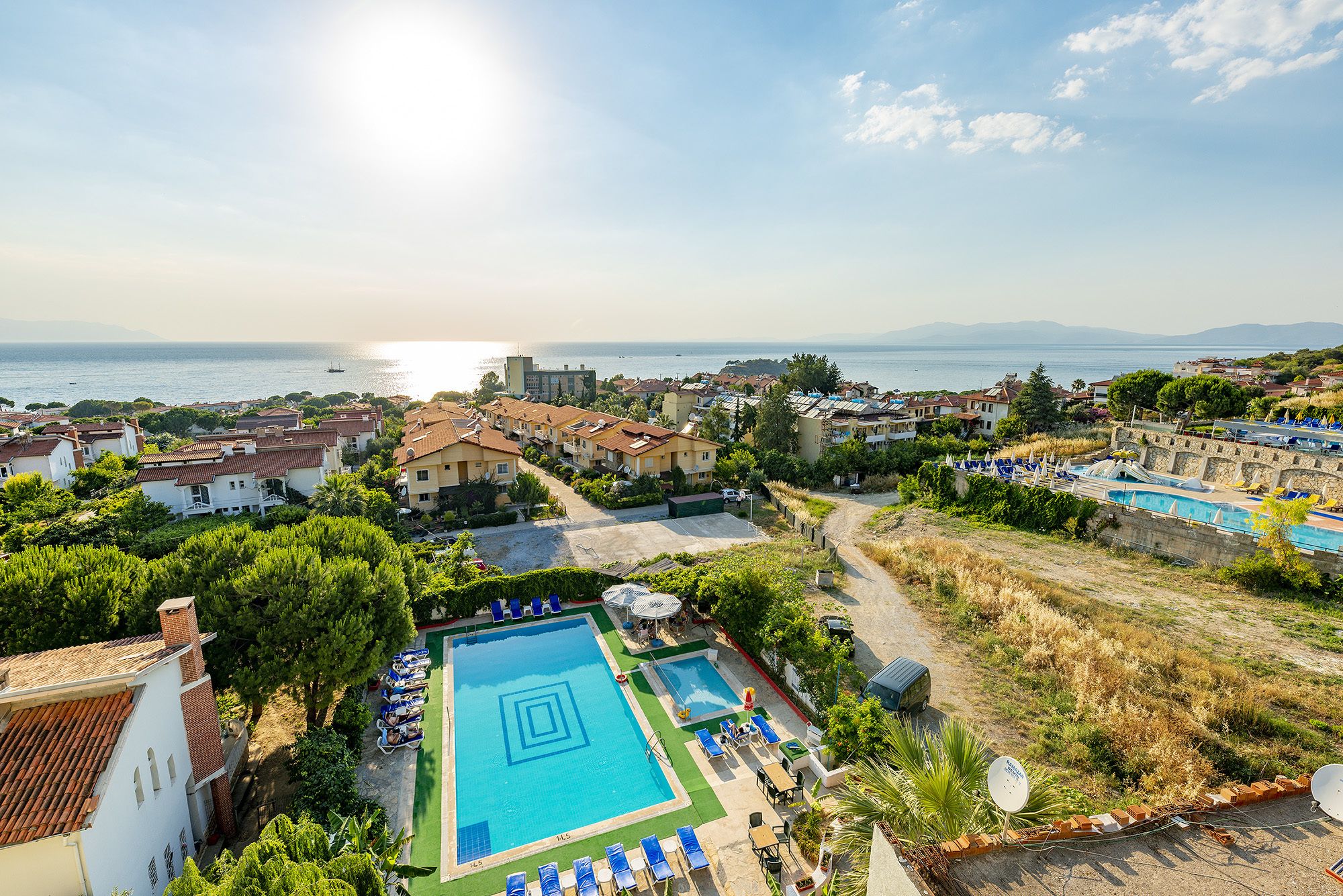 A resort with a swimming pool, lounge chairs, and a view of the sea.