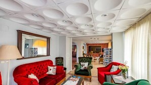 A hotel lobby with a red sofa, green armchairs, a coffee table, and a bookshelf. - Alibabam Apart Hotel (Kusadasi)