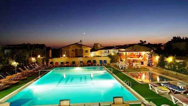 A swimming pool with lounge chairs and a building in the background. - Alibabam Apart Hotel (Kusadasi)