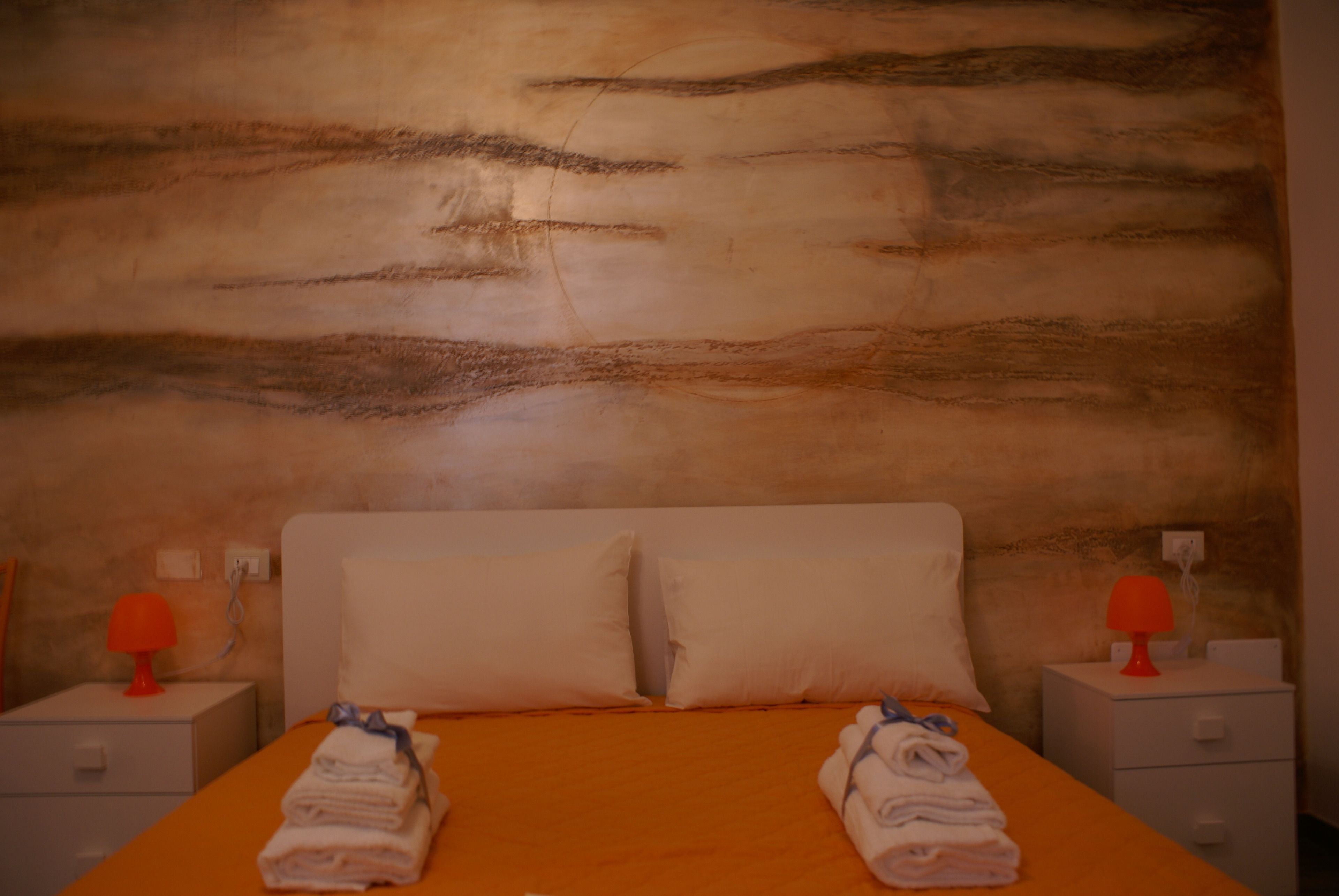 A hotel room with a bed, two nightstands, and a textured wall.