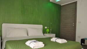 A neatly made double bed with green bedding, a bedside table with a lamp, and a closed wardrobe. - Alicata B&B La Dimora Del Vento (Licata)