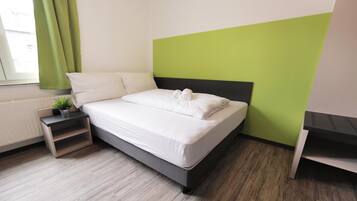 Un dormitorio moderno con una cama, una mesita de noche, una planta en maceta y vistas al exterior.