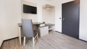 Een moderne kamer met een bureau, stoel, televisie en kledingkast.