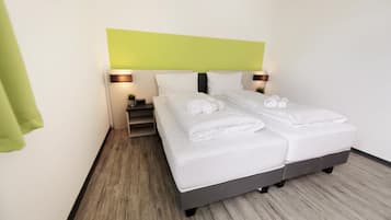 A hotel room with a bed, two bedside tables, and a green wall.