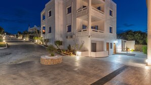A multi-story building with a central courtyard, balconies, and a well-lit entrance. - Aelia Apartments (Hersonissos)