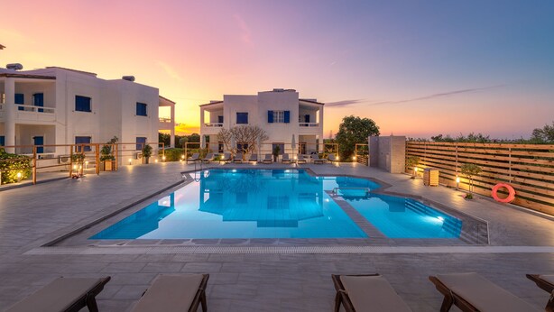A pool area with lounge chairs and a sunset view. - Aelia Apartments (Hersonissos)
