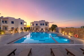 A pool area with lounge chairs and a sunset view.