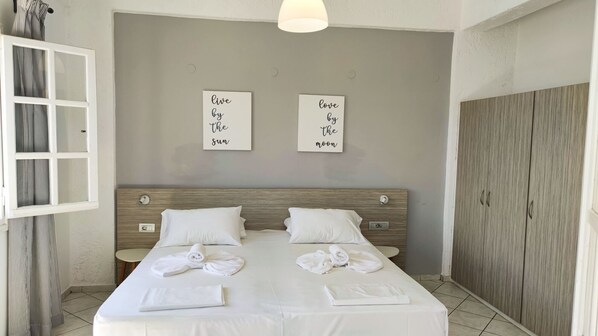 A hotel room with a bed, two nightstands, a wooden wardrobe, and two wall art pieces with motivational phrases.