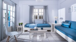 A modern room with a bed, a sofa, a table with a tray of items, and a chair. - Aelia Apartments (Hersonissos)