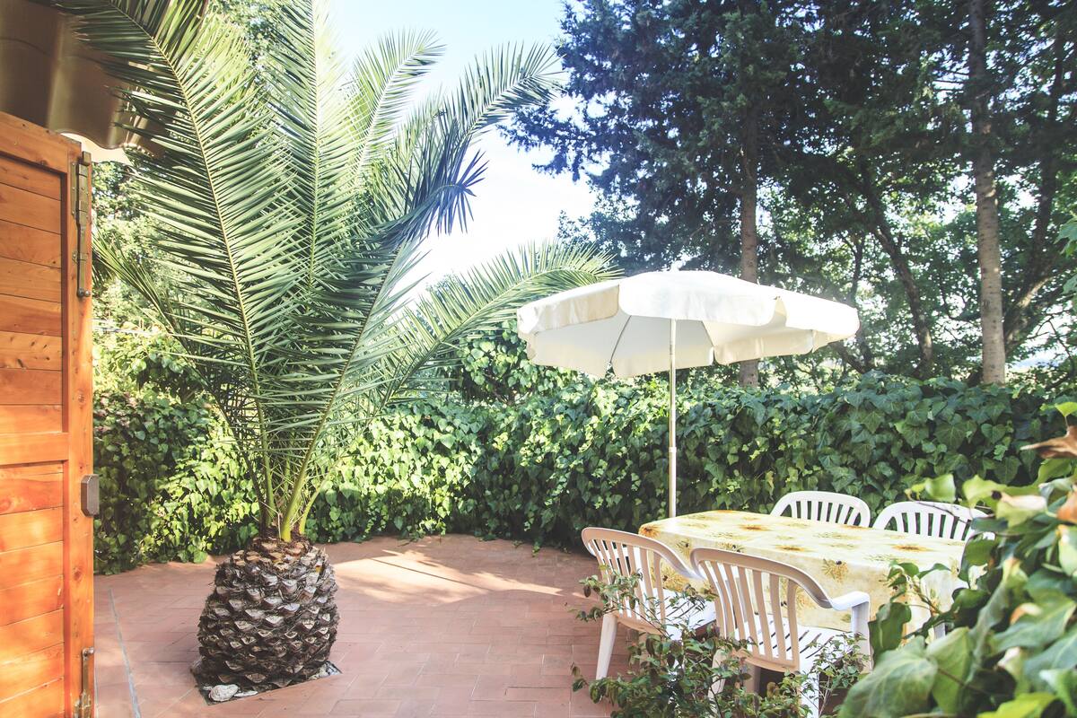 An outdoor patio with a wooden door, a table with chairs, and a large umbrella.