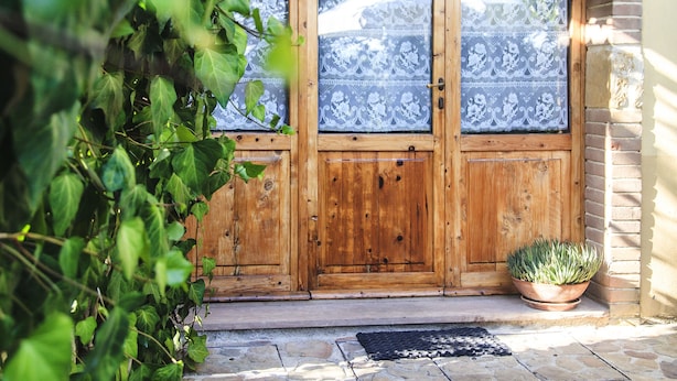 A wooden door with a glass panel, a stone-paved entrance, and a potted plant. - Podere Risoino (Poggibonsi)