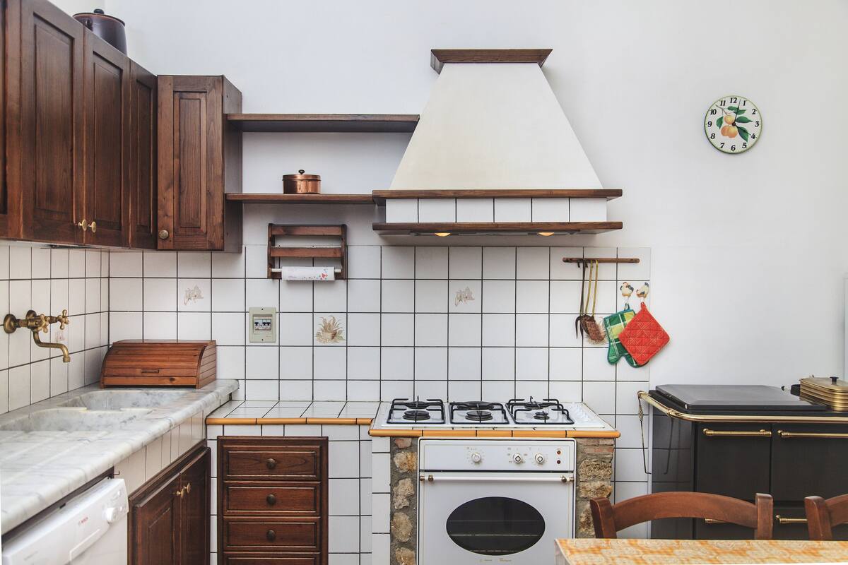 A kitchen with wooden cabinets, a gas stove, a built-in oven, and a tiled backsplash.