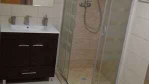 A bathroom with a glass-enclosed shower, a toilet, and a sink. - Bela & Nunes (Lagoa)