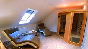 Camera da letto moderna mansardata con lucernario, una poltrona integrata, un tavolino e un armadio con porta scorrevole in vetro.