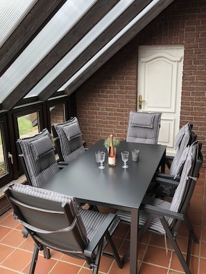 A dining area with a dark table, six striped chairs, two wine glasses, and a bottle of champagne.