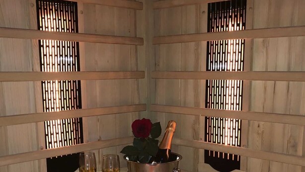 Una stanza in legno con un tavolo apparecchiato per due, con una bottiglia di champagne, due bicchieri e una rosa rossa.