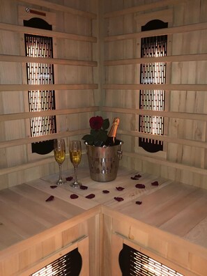 A wooden room with a table set for two, featuring a champagne bottle, two glasses, and a red rose.