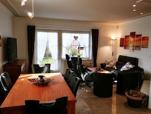 Un salon moderne comprenant un coin repas, de grandes fenêtres, une cheminée et une vue sur un jardin.