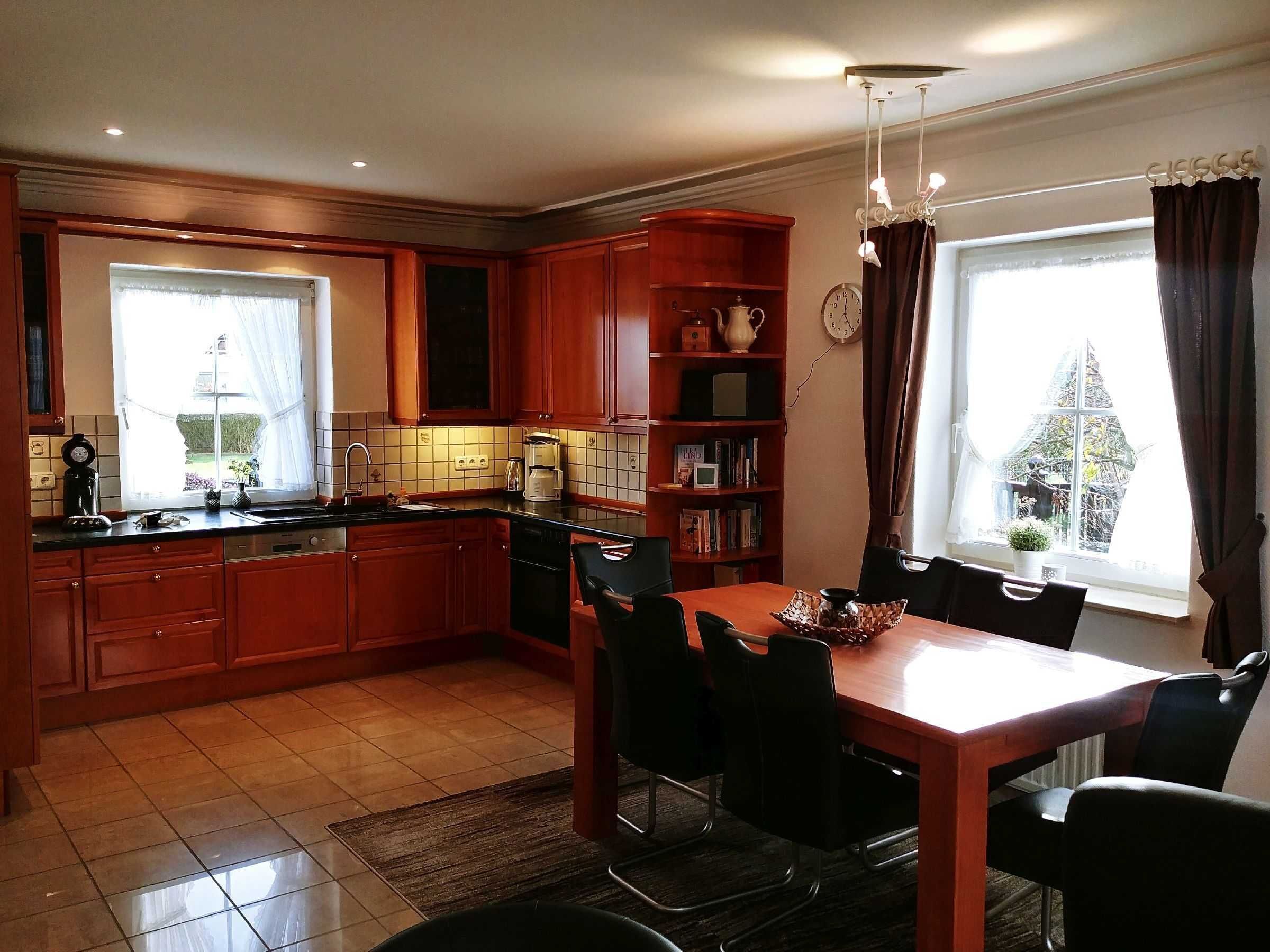 Una cucina con mobili in legno, un tavolo da pranzo con sedie, una macchina per caffè e una libreria.