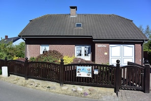 Un bâtiment en briques avec un toit en tuiles, une porte blanche et une enseigne.