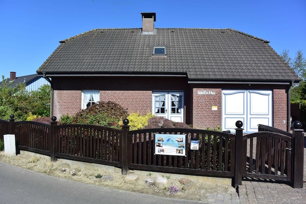 A brick building with a tiled roof, a white door, and a signboard.