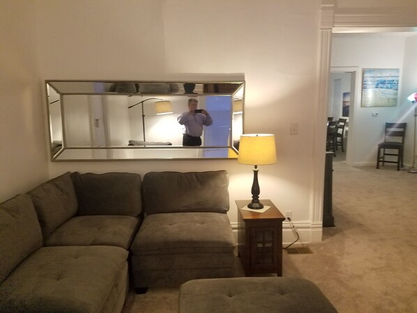 A living room with a sofa, a lamp, and a mirror.