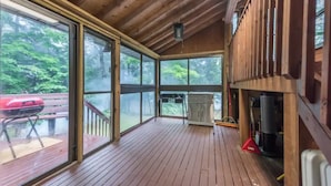 A covered wooden deck with large windows, a barbecue grill, and a fireplace. - Crystal Palace Cottage, Kawartha Lakes (Kinmount)
