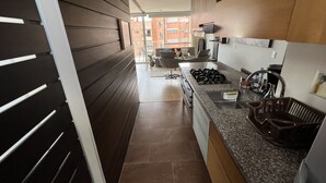 A modern kitchen with a central island, built-in appliances, and a view to the outside.