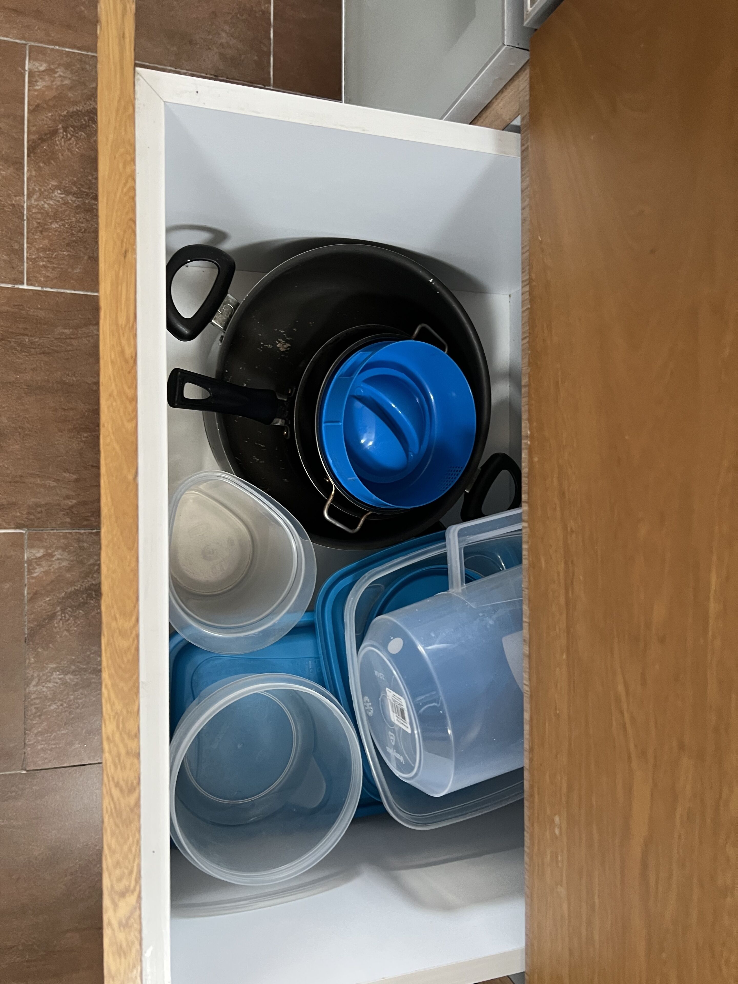 A kitchen drawer with various containers and cookware.