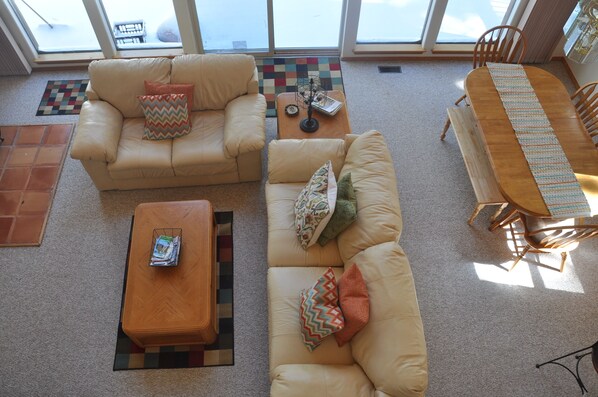 A spacious living area with a beige sofa, a wooden coffee table, and a dining table with chairs.