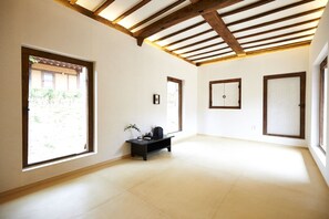 Una habitación amplia con ventanas grandes, techo de madera y una pequeña mesa negra con una planta.