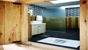 Een badkamer met houten kozijnen, voorzien van een wastafel, kastruimte en douchehoek.