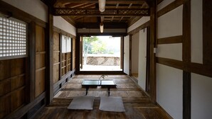 Een traditionele Japanse kamer met tatami vloerbedekking, een lage tafel met een vaas en uitzicht op een tuin door een schuifdeur.