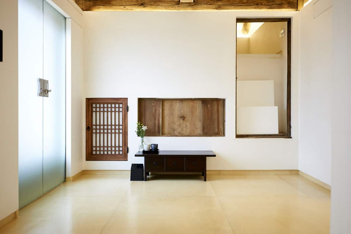 A room with a wooden cabinet, a large mirror, and a small table with a vase.